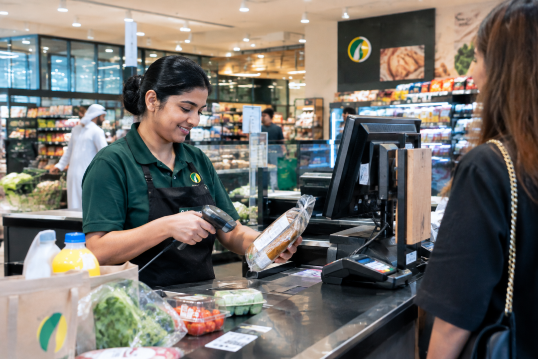 Spinneys cashier working at a supermarket checkout in Dubai